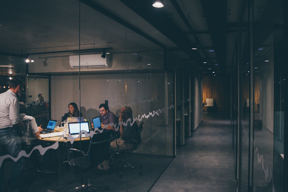 A team working late behind a glass wall, deep in a focused session