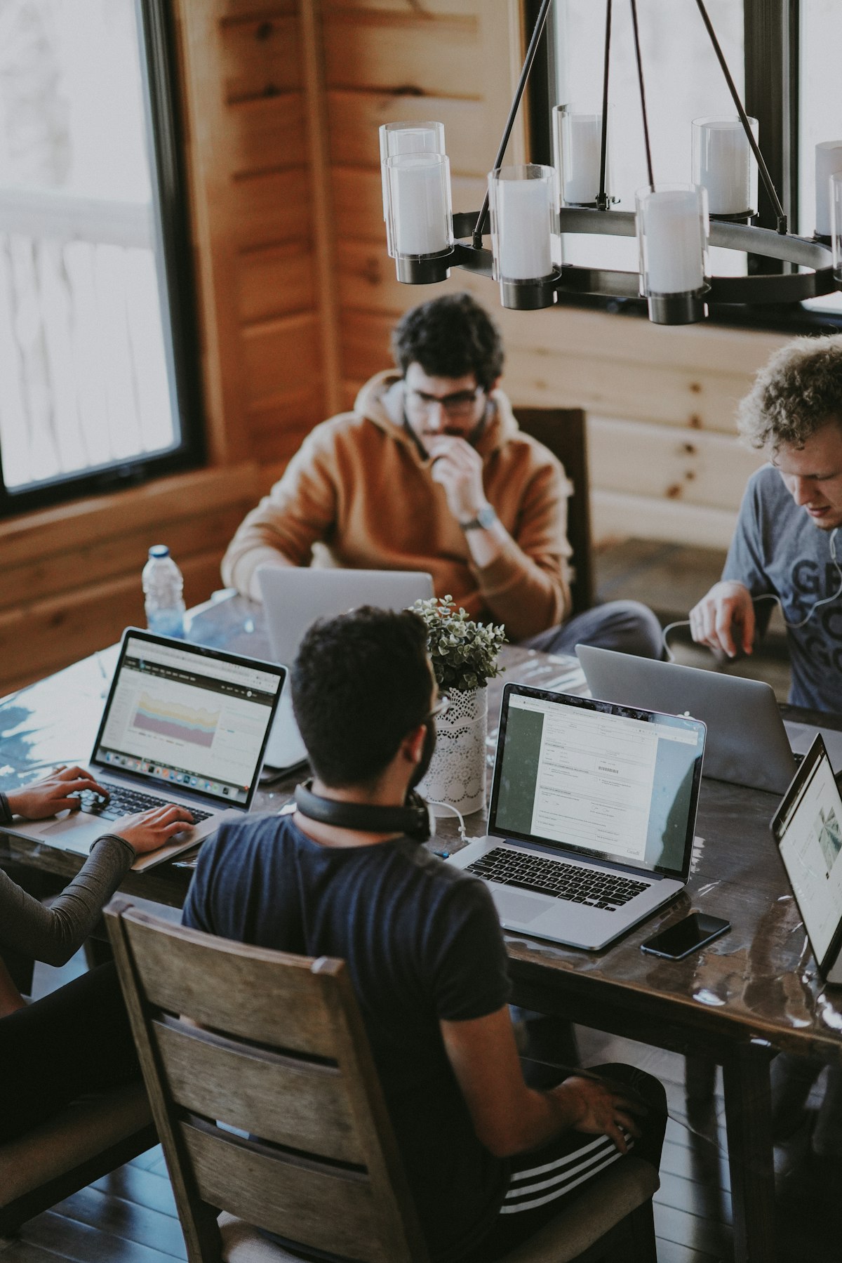 Team working on laptops around a wooden table in a bright modern office